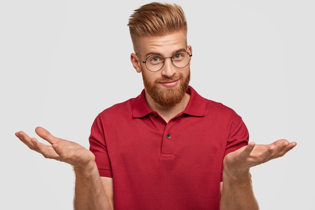doubtful-attractive-bearded-young-male-with-ginger-hair-thick-beard-mustache-shruggs-shoulders-doubts-what-buy-has-appealing-look-poses-against-white-wall-hesitation-concept_273609-16408-1